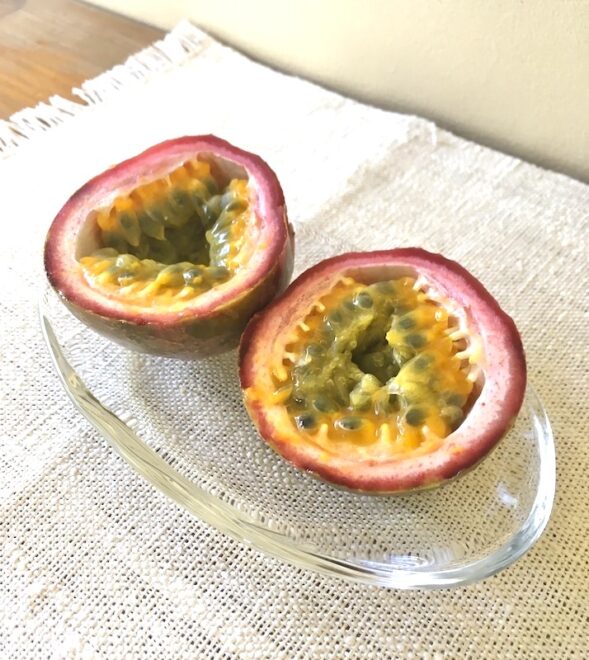 半分にカットしてガラスのお皿に乗っているパッションフルーツ